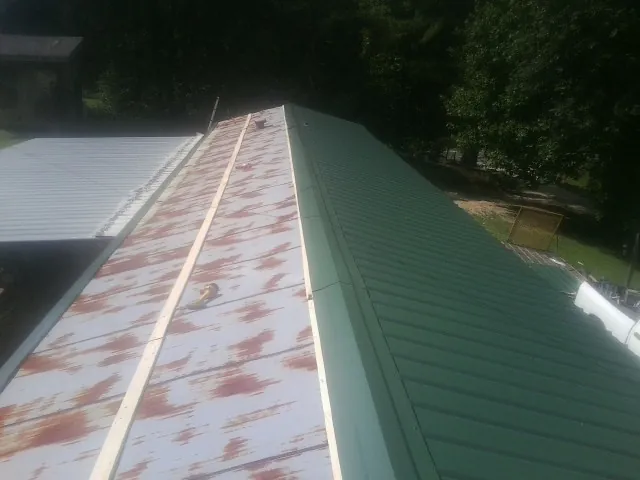 Old rusted panels beside newly installed green metal roofing — Wind Damage Roof Repair by Roofing Brothers in Ware