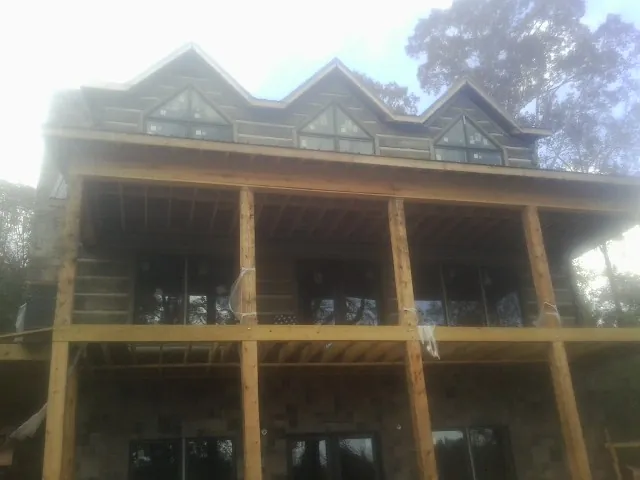 Dormers and porch framing on a large log home under construction — Roof Coating work by our crew in Ware